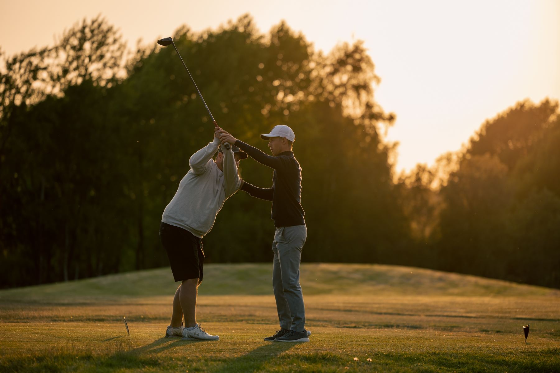 Birk coachar en spelare på tee i solnedgången